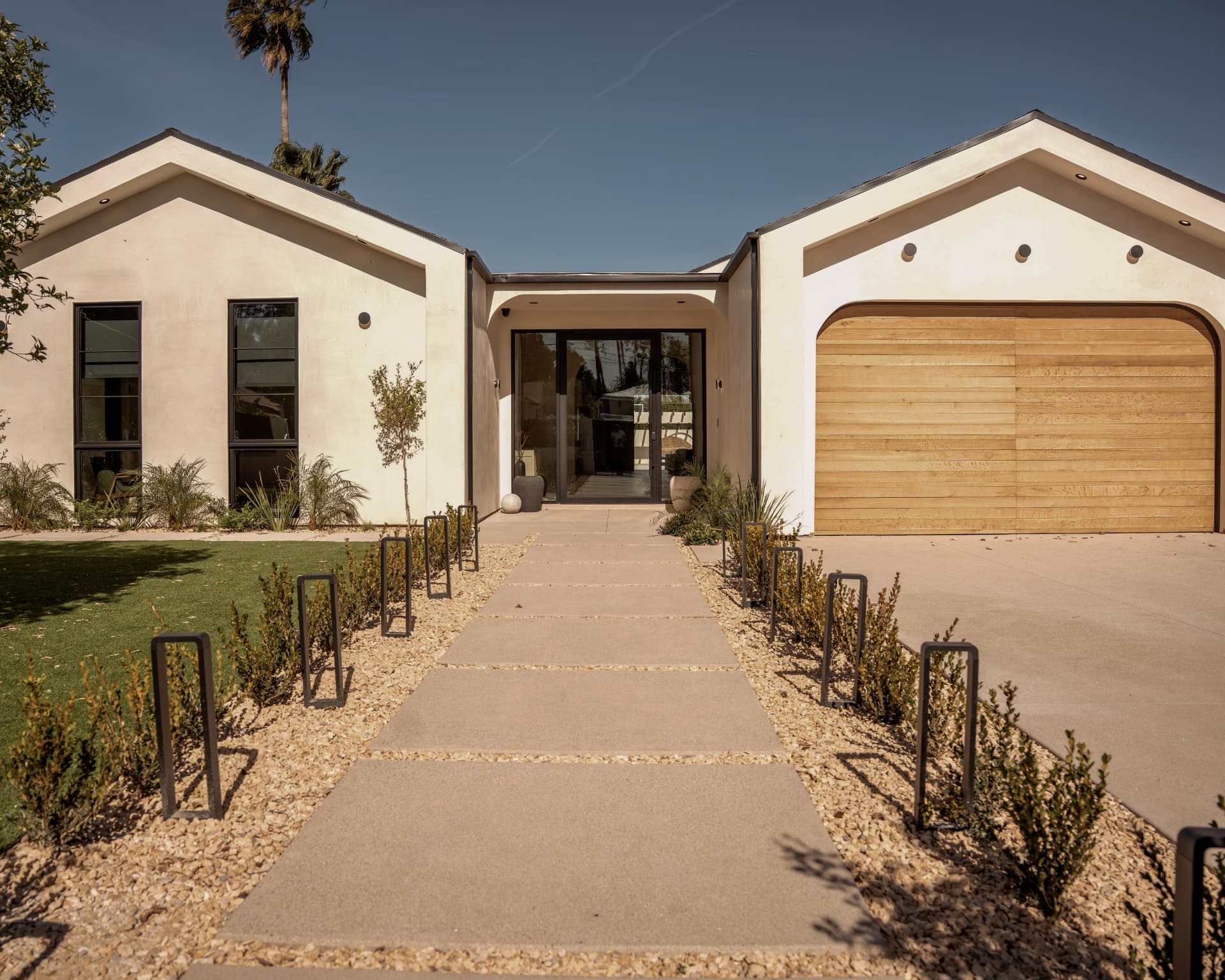 Modern single-story Sherman Oaks residence with symmetrical gables, wood garage door and landscaped entry path