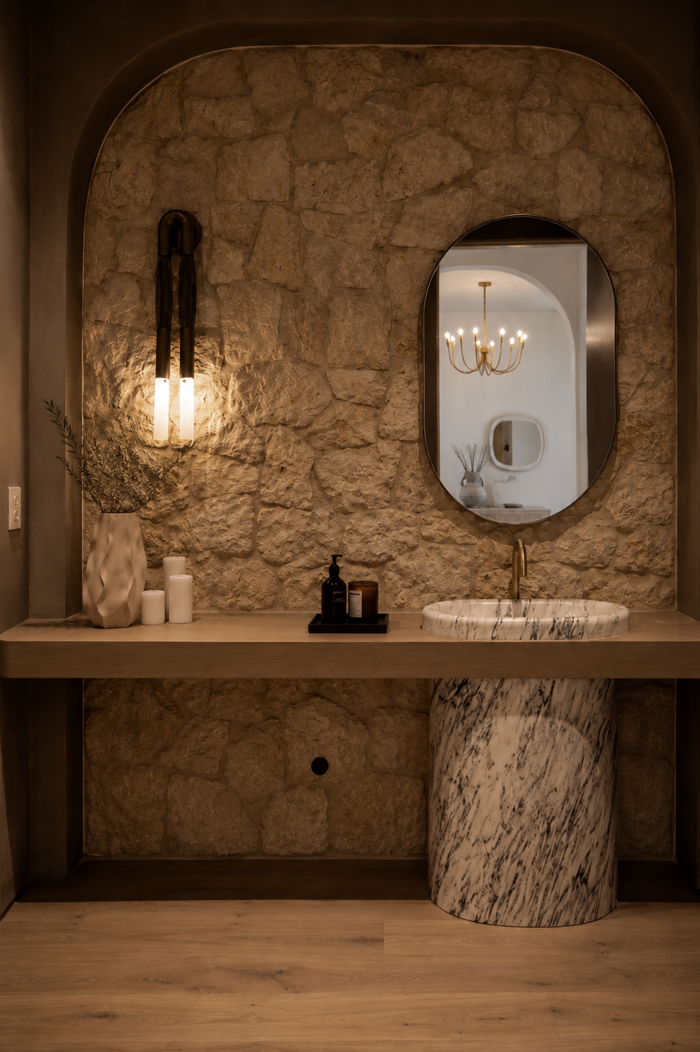 Powder room with rough stone wall, marble sink and arched mirror